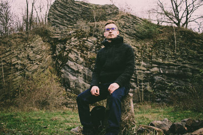 Man sitting on tree stump in forest