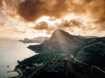 Scenic view of sea and mountains against sky during sunset