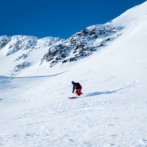 Man skiing on snowcapped mountain against sky