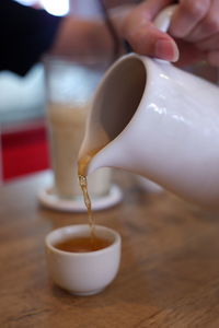 Close-up of hand holding tea cup on table