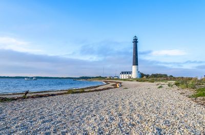 Lighthouse by sea against sky