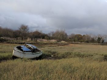 Abandoned boat on field against sky