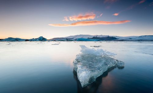 Iceberg on frozen lake against sky