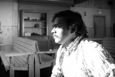 Thoughtful man sitting on chair at restaurant during sunny day