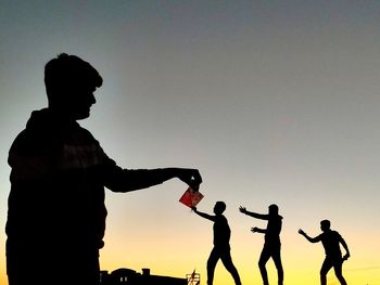 Silhouette people against clear sky during sunset