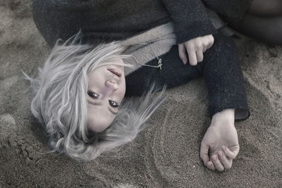 High angle portrait of sad woman lying on sand at beach