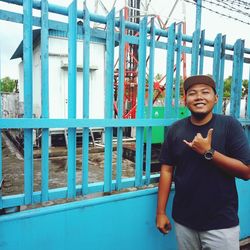 Portrait of young man standing against railing