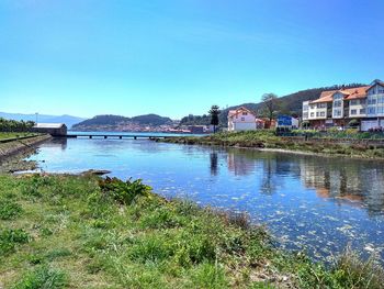 Scenic view of river by houses against clear blue sky