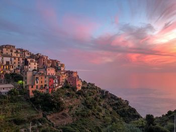 Buildings on mountain against sky during sunset