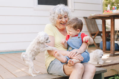 Grandmother sitting with grandson boy on porch at home backyard. old woman with baby having fun 