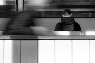 Rear view of people standing on platform with train arriving