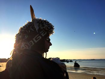 Portrait of man looking at sea shore against sky during sunset