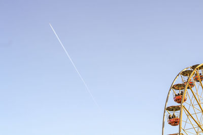 Low angle view of ferris wheel against clear blue sky