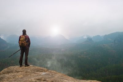 Rear view of man standing on mountain against sky