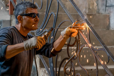 Man wearing protective glasses welds metal with welding machine in a private house.  close-up.