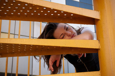 Young woman lying down on spiral staircase outdoors