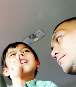 Low angle view of man looking at son picking nose in car