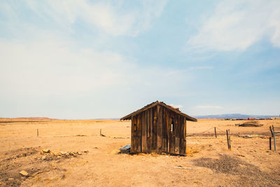 Wooden hut on field against sky