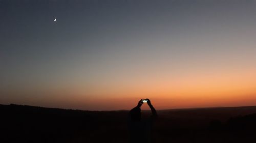 Scenic view of silhouette land against clear sky at sunset