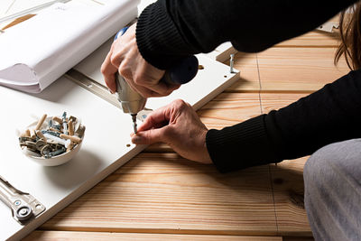 Cropped hands drilling on wood