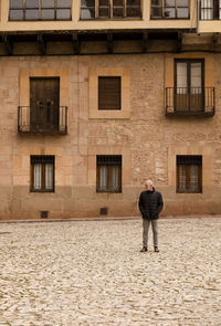 Adult man in winter clothes standing against old building. siguenza, castilla la mancha, spain