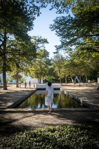 Rear view of woman standing by pond in park