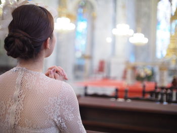 Rear view of young woman praying in church