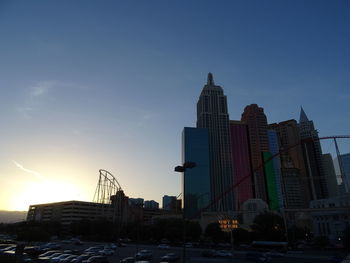 Modern buildings in city against sky during sunset