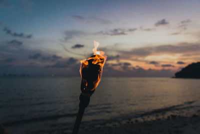 Man with umbrella on beach during sunset