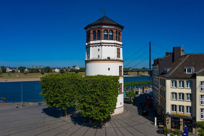 View of lighthouse and buildings against clear blue sky