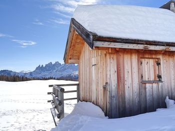 House on snow covered landscape against sky