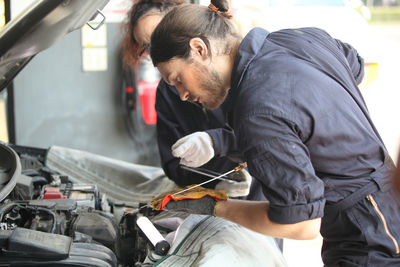 Rear view of man working on motorcycle