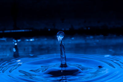 A drop that forms a sculpted pillar and makes rings on blue water
