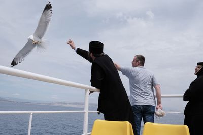 Men standing by sea against sky