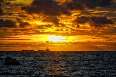 Scenic view of sea against dramatic sky during sunset