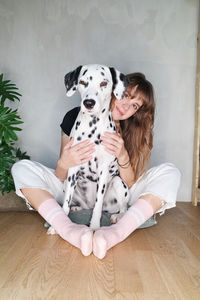 Midsection of woman with dog sitting on hardwood floor at home