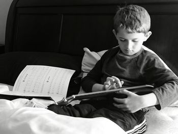 Boy playing guitar on bed at home