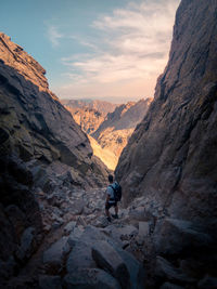 Man on rock formation against sky