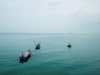 Fishing boats in sea against sky