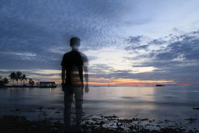 Double exposure of man standing on shore at beach against sky during sunset