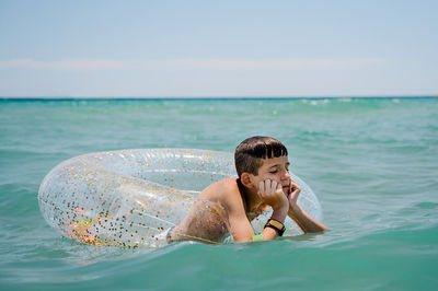 Boring white boy swimming in a float in turquoise mediterranean sea