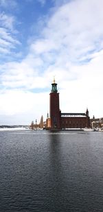 Lighthouse on building by sea against sky