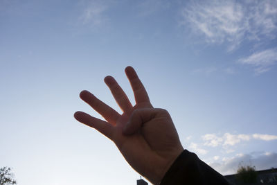 Low angle view of person hand against sky
