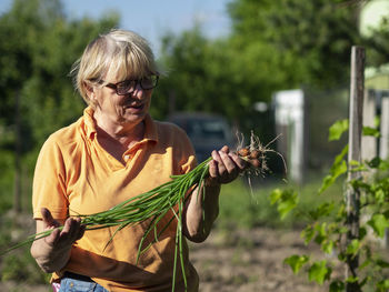 Woman holding plants on field