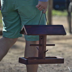 Midsection of man holding umbrella while standing on wood