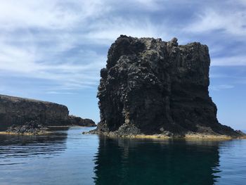 Rock formations by sea against sky
