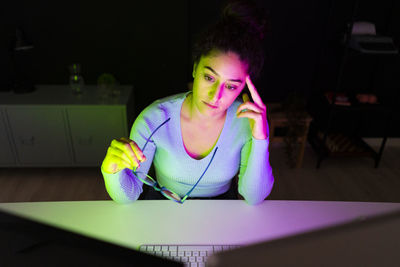 Worried businesswoman holding eyeglasses looking at desktops at home office