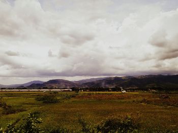 Scenic view of field against cloudy sky