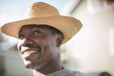 Smiling mid adult man looking away while wearing straw hat during garden party