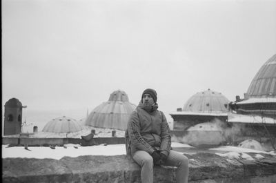 Low angle view of man sitting on a roof against sky